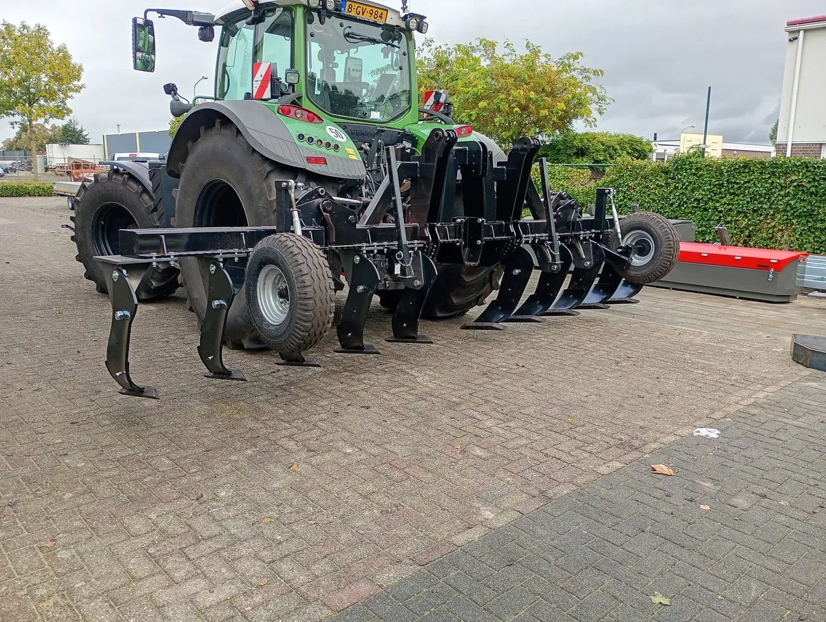 Zwarte diepwoeler met steunwielen achter een groene Fendt-trekker