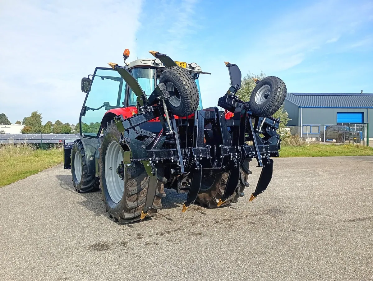Zwarte diepwoeler met steunwielen achter een rode trekker